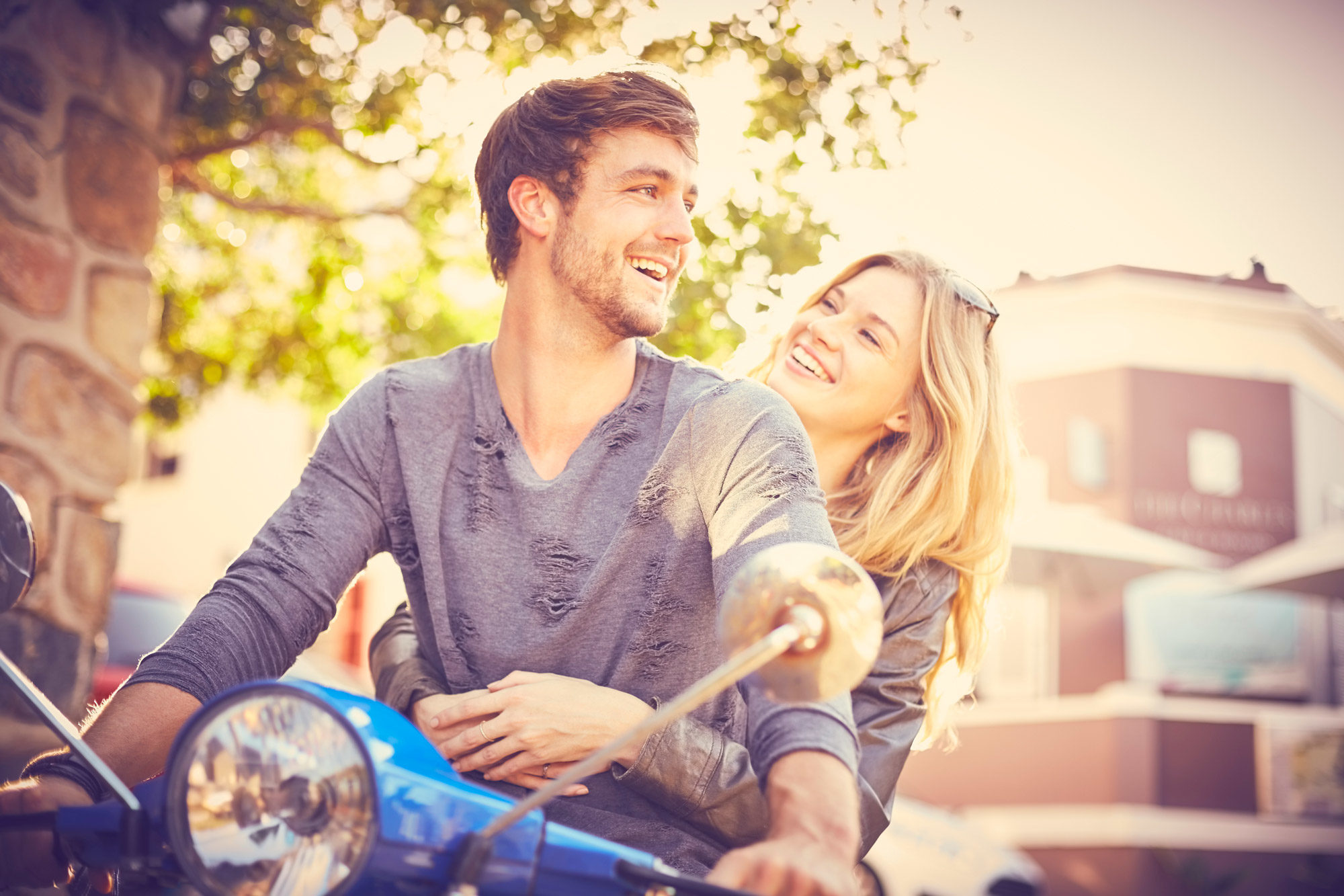 Man and woman smiling on moped